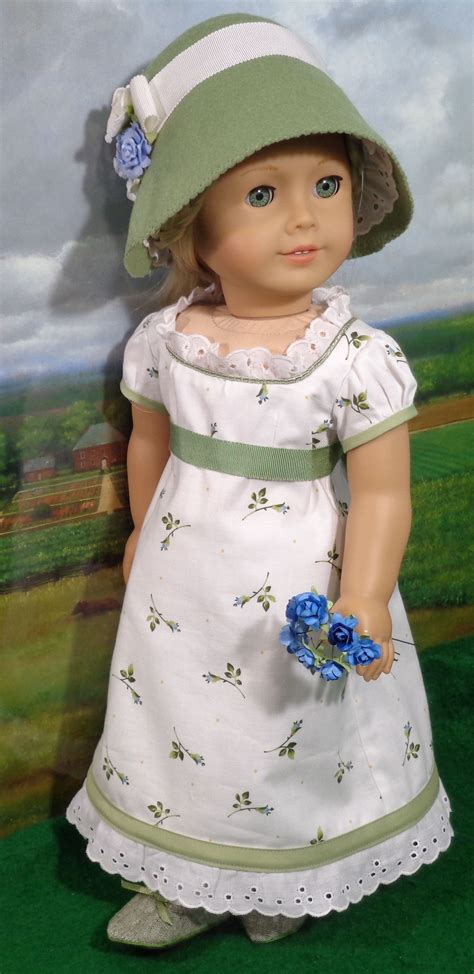 A Doll Wearing A White Dress And Green Hat With Blue Flowers On Its Head