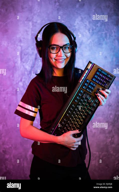 beautiful friendly pro gamer streamer girl posing with a keyboard in her hands wearing glasses