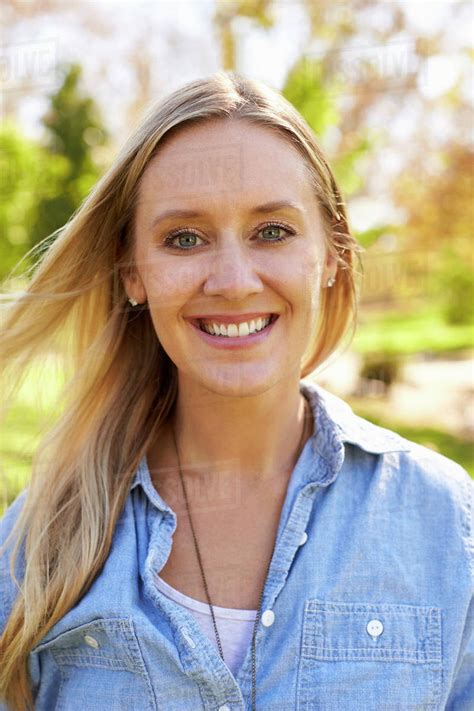 Mid Thirties White Woman Smiling To Camera In Park Vertical Stock