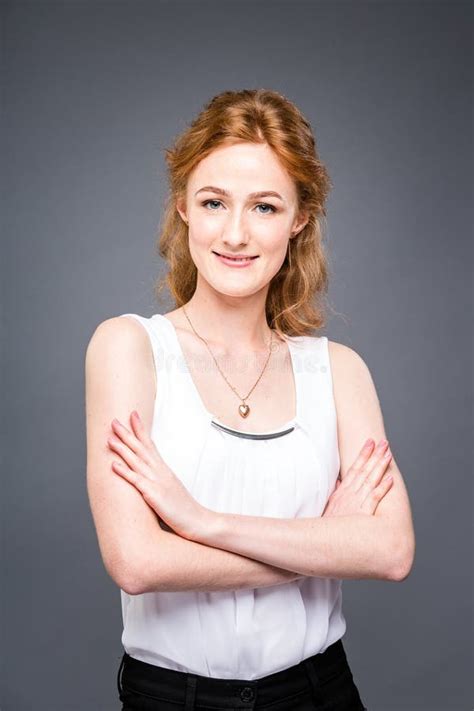 Portrait Of A Young Redhaired Beautiful Girl In The Studio On A Gray