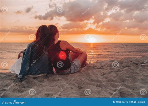 couple of lesbian girls sitting on the beach and watching and enjoying a beautiful sunset