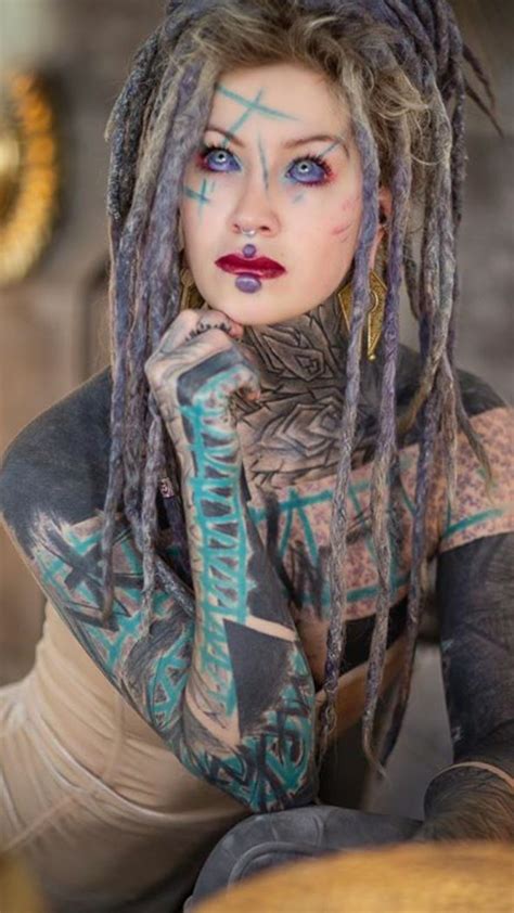 A Woman With Dreadlocks And Tattoos On Her Body Is Posing For The Camera