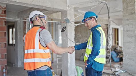 Two Men Builders Shake Hands Speaking At Construction Site Stock