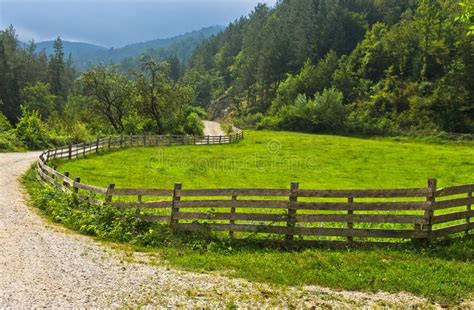 Winding Country Road With Old Wooden Fence And Green Meadow Stock Photo