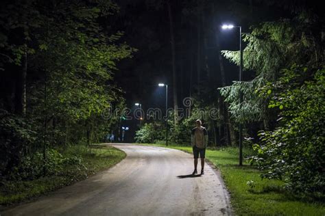 Alone Young Man In Casual Walking On The Night Forest Road With The