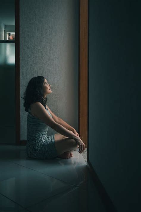 Side View Photo Of Woman Sitting On Floor In Front Of Doorway With Her