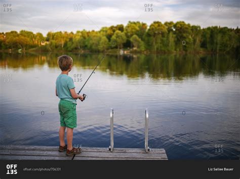 A Young Boy Fishing Alone Off A Dock Stock Photo Offset