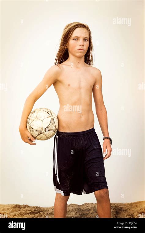 Portrait Of Shirtless Boy Holding Soccer Ball Standing Against Clear
