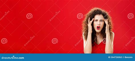annoyed and displeased cute feminine redhead curly woman shut ears with fingers squinting and