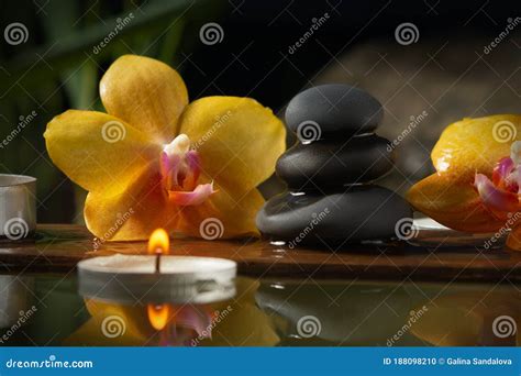 Black Zen Stones Candles And Yellow Orchids On A Wooden Plank On The