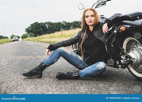 Pretty Girl Biker Sitting Near Her Motorcycle On The Asphalt Road Stock