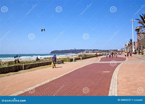 People Walking Along Paved Promenade On Beach Front Editorial