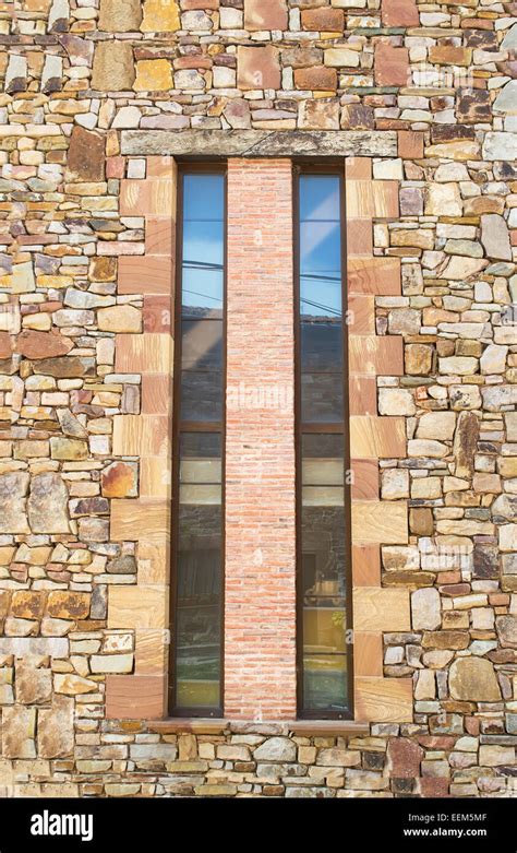 Long Vertical Windows Separated By A Layer Of Decorative Bricks On A Stone Plated Wall Stock