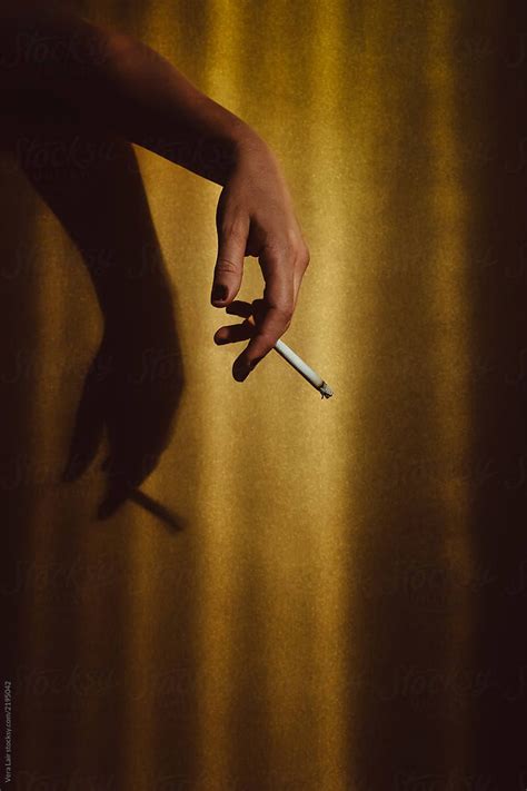 Womans Hand Holding A Cigarette On A Golden Background By Vera Lair