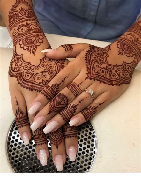 Two Hands With Henna Tattoos On Them And One Holding The Others Hand