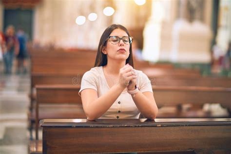 Young Beautiful Woman Praying On Her Knees In A Bench At Church Stock
