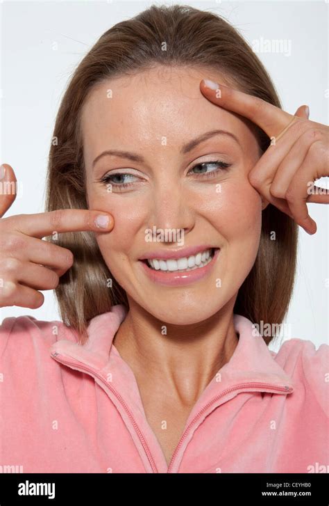 Female Fair Hair Off Her Face Wearing A Pink Jacket Squeezing Spots On Her Forehead And Cheek