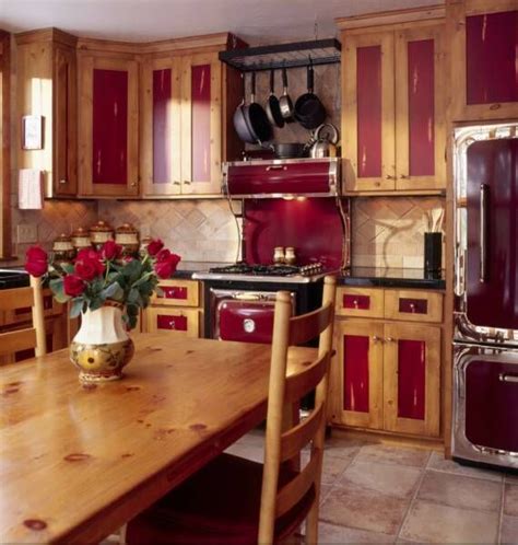A Kitchen With Red Cabinets And Wooden Table In The Foreground Is An