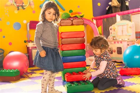 Premium Photo Two Girls Play With Big Bricks In Playroom
