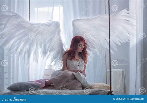 Oung Model With Open Angel Wings And Pink Dress Sitting On Hanging Bed