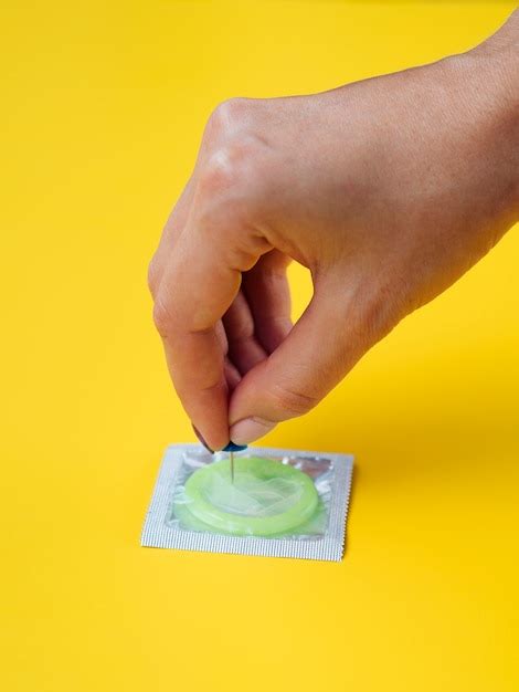 Free Photo Close Up Hand Stinging A Condom With A Pin