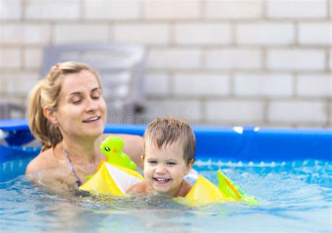 Mom Plays With A Naked Baby In Oversleeves In The Pool Against The