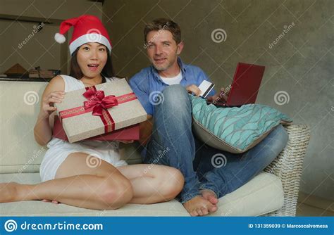 Young Happy And Excited Mixed Ethnicity Couple With Asian Chinese Woman In Christmas Hat And