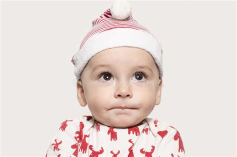 Portrait Of A Cute Baby Boy Looking Up Thinking Wearing A Santa Hat