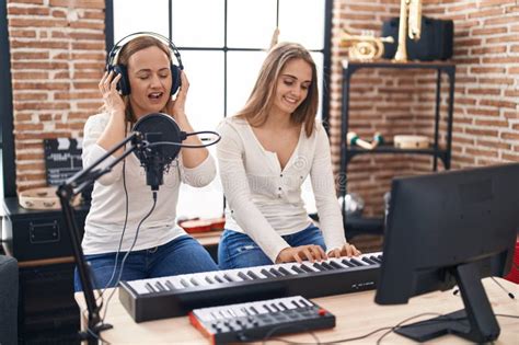 Two Women Musicians Singing Song Playing Piano At Music Studio Stock