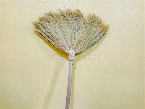 A Yellow Palm Fiber Broom Against A Yellow Wall Background Stock