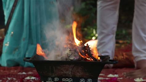 bride and groom walk around the sacred fire at the indian wedding ceremony and they throw rose