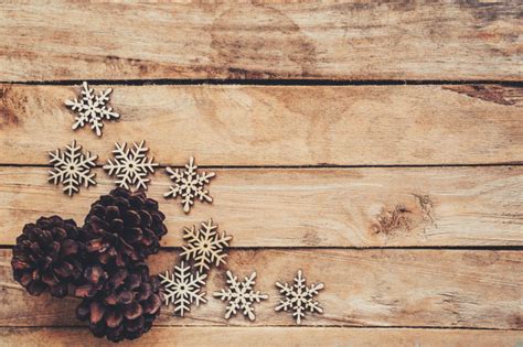 Fröhliche und erholsame weihnachtstage wünschen euch. Tannenzapfen und schneeflocken auf holz für weihnachten hintergrund mit platz. | Premium-Foto