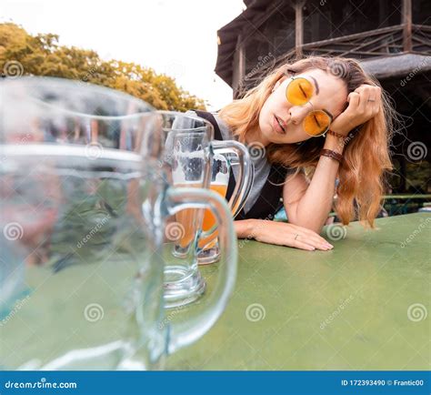 Drunk Asian Girl With Hangover Sleeping In Biergarten With Empty Beer
