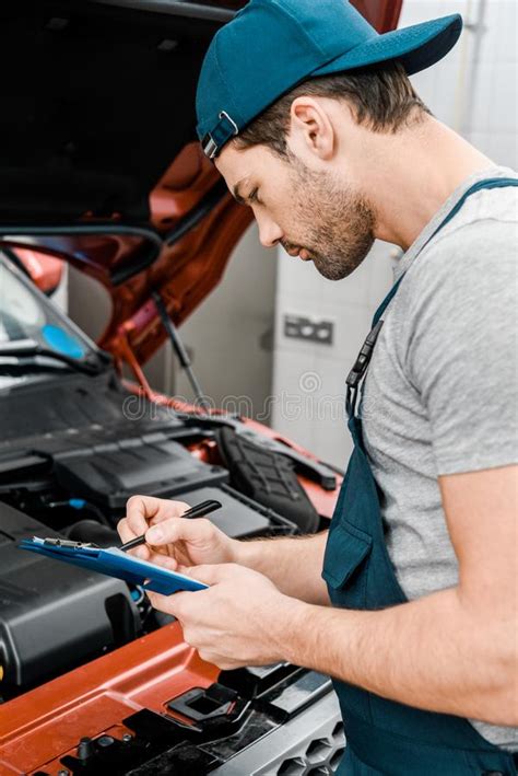 Side View Of Repairman With Notepad Examining Car Stock Image Image