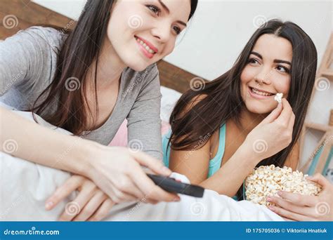 Lesbian Couple In Bedroom At Home Lying Watching Tv One Woman Holding Remote Controller Close Up