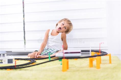 Un Chico Lindo Jugando Con Un Camino De Tren De Juguete En Casa En El Piso Imagen De Archivo