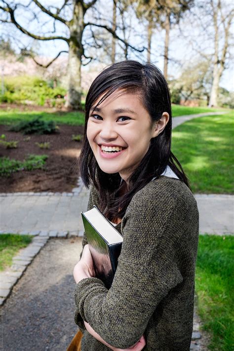 Asian College Student Carrying A Book On Campus Del Colaborador De