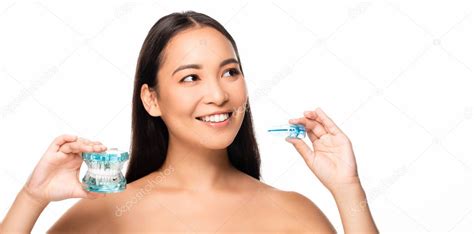 desnudo sonriente asiático mujer holding maxilar modelo y boca guardia aislado en blanco