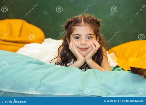 colorful portrait of little cheerful armenian girl lying and keeping her hands under chin stock