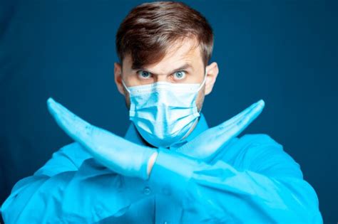 premium photo doctor in a medical mask and gloves in a blue uniform on a blue background