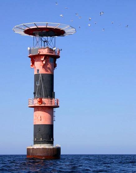 a light house in the middle of the ocean with birds flying around and