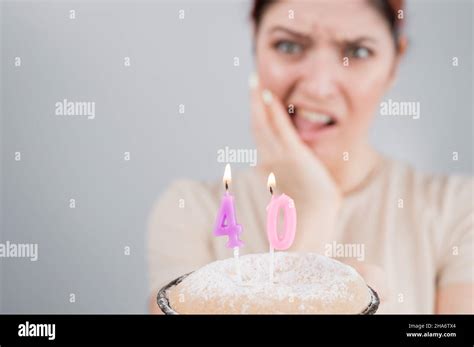 unhappy woman holding a cake with candles for her 40th birthday the girl cries about the loss