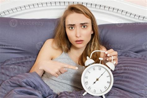 Shocked Young Woman Waking Up With Alarm Girl Point On Clocks In Bed