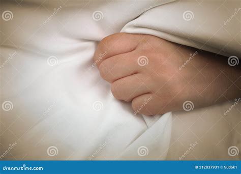 Female Patient Gripping A Fistfull Of The Bed Sheets In One Hand Stock