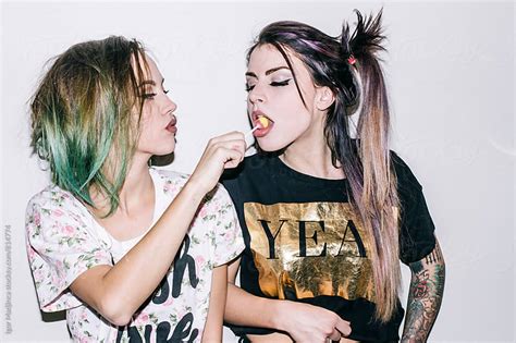 Two Fashionable Tattooed Girls With Colorful Hairstyles Eat Candy Direct Light By Igor Madjinca