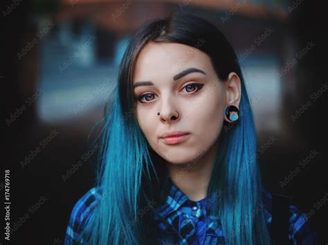 street punk or hipster girl with blue dyed hair woman with piercing in nose violet lenses