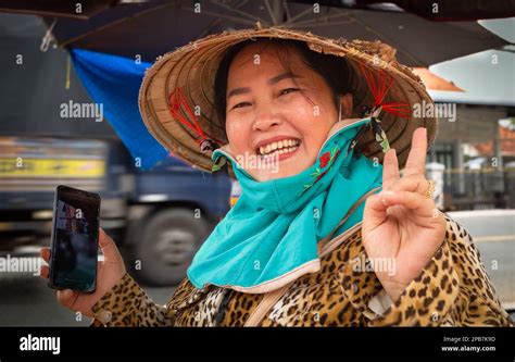 une femme vietnamienne portant un chapeau conique traditionnel et tenant un téléphone mobile