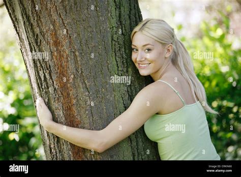 A Young Blond Woman Hugging A Tree Smiling Stock Photo Alamy