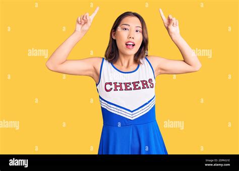 Young Beautiful Chinese Girl Wearing Cheerleader Uniform Smiling Amazed