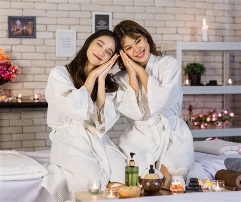Portrait Shot Of Two Asian Young Beautiful Cheerful Female Spa Customers In White Clean Bathrobe